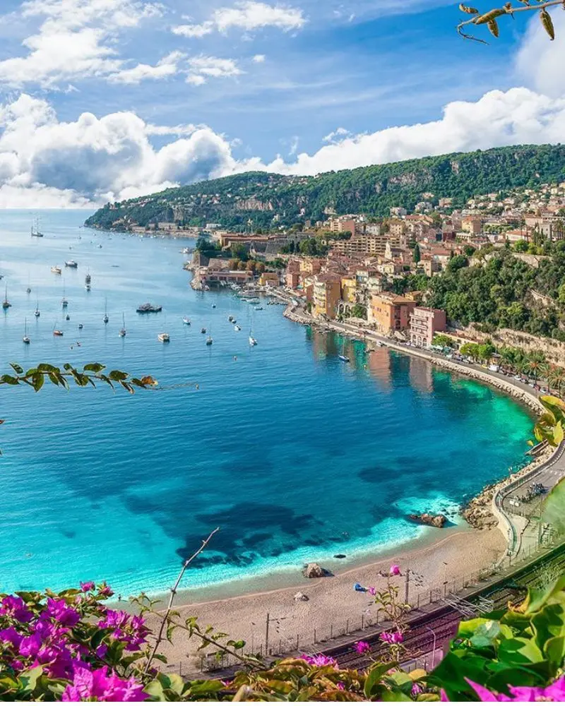 Bahía turquesa de Villefranche-sur-Mer con playa en media luna y fachadas de colores