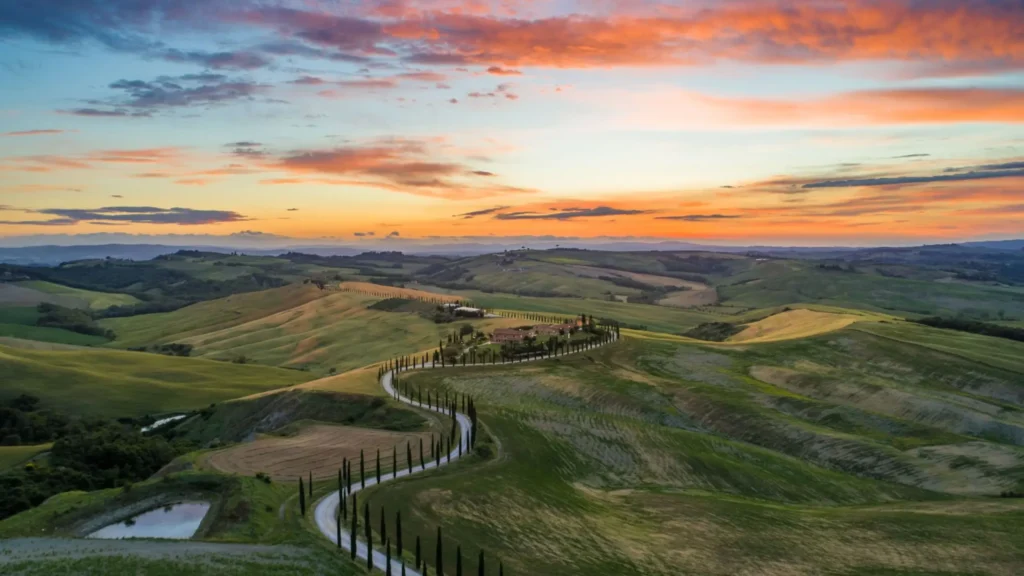 Carretera serpenteante de cipreses entre colinas de la Toscana al atardecer (zona Siena)